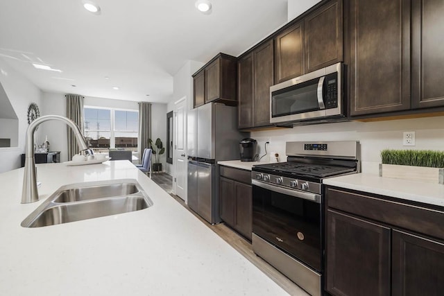kitchen with light countertops, stainless steel appliances, a sink, and dark brown cabinets