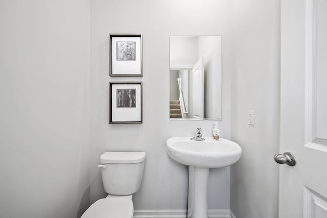 half bathroom featuring a sink, baseboards, and toilet