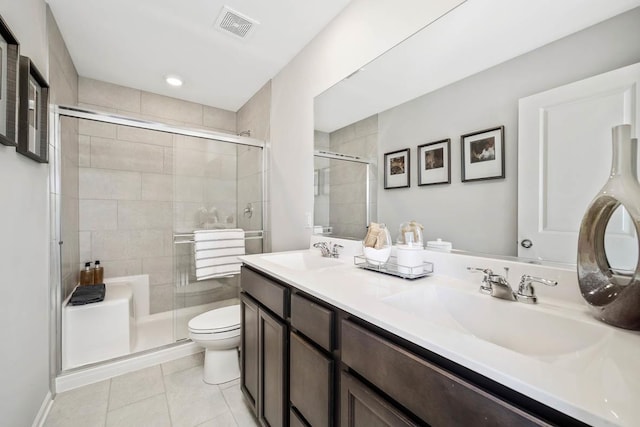 bathroom featuring toilet, a shower stall, a sink, and tile patterned flooring