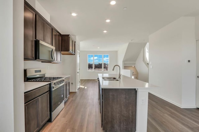 kitchen featuring a sink, baseboards, dark brown cabinetry, and stainless steel appliances
