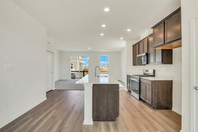 kitchen with light wood-type flooring, a sink, appliances with stainless steel finishes, and dark brown cabinets