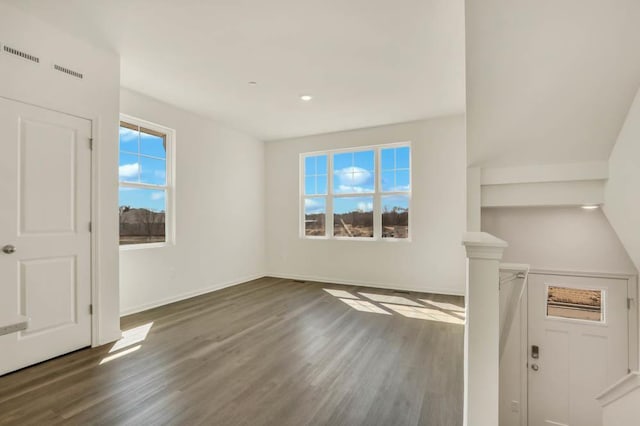 unfurnished living room with visible vents, a wealth of natural light, and wood finished floors