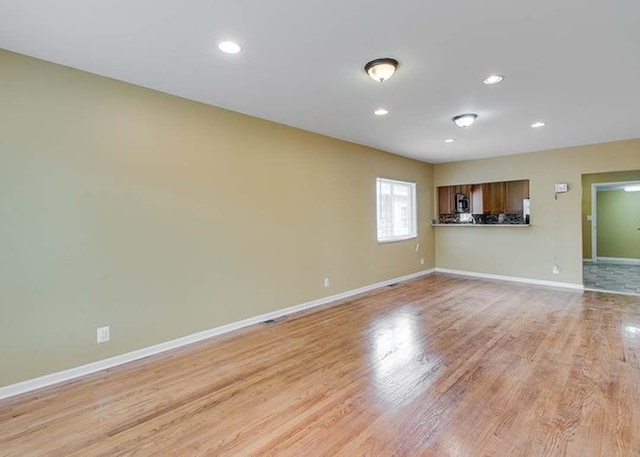 unfurnished living room with baseboards, recessed lighting, and light wood-style flooring