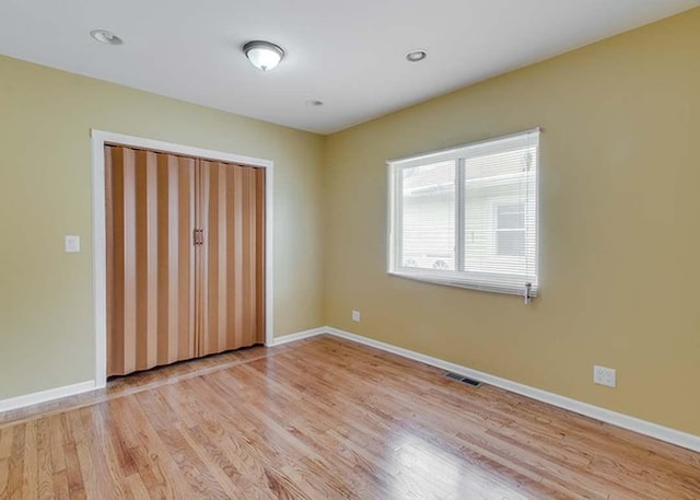 unfurnished bedroom with visible vents, light wood finished floors, baseboards, and a closet