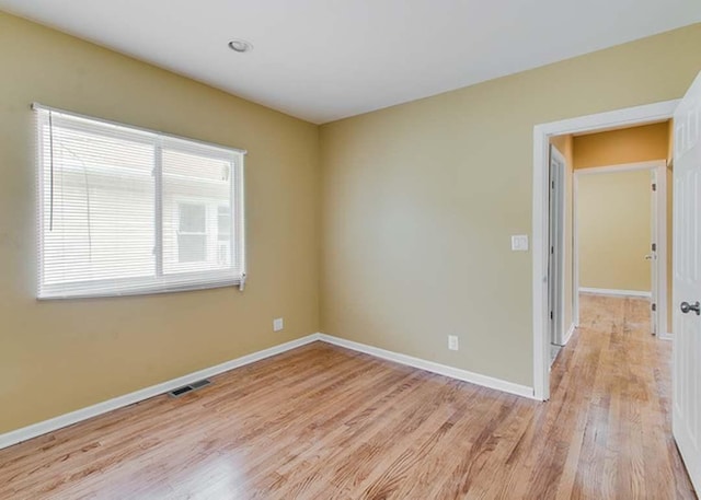 spare room featuring baseboards, light wood-type flooring, and visible vents