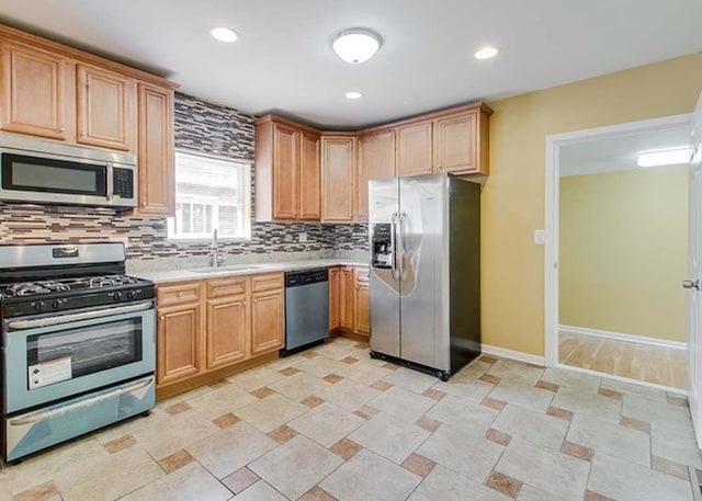 kitchen with decorative backsplash, baseboards, light countertops, a sink, and stainless steel appliances