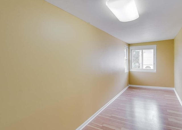 spare room with baseboards and light wood finished floors