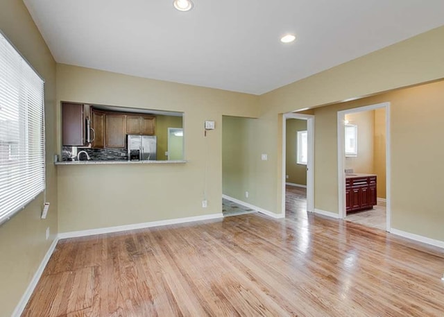 unfurnished living room featuring recessed lighting, baseboards, and light wood finished floors