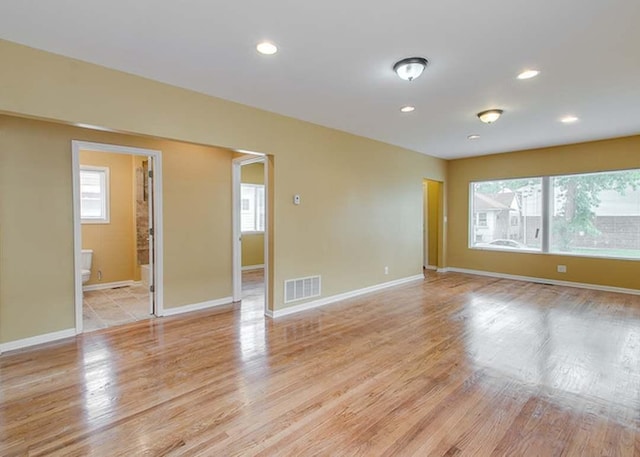 unfurnished room with plenty of natural light, baseboards, and light wood-type flooring