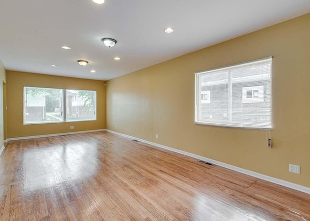 spare room featuring baseboards, light wood finished floors, and visible vents