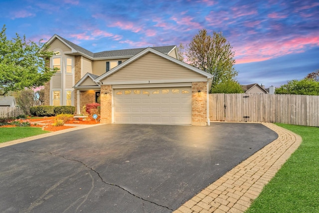 traditional home with fence, brick siding, a garage, a gate, and driveway