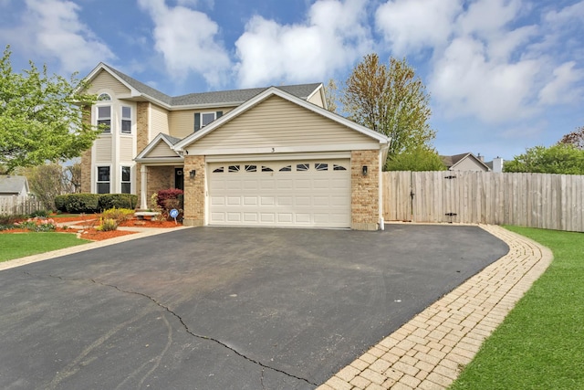 traditional-style house with brick siding, a garage, fence, and aphalt driveway