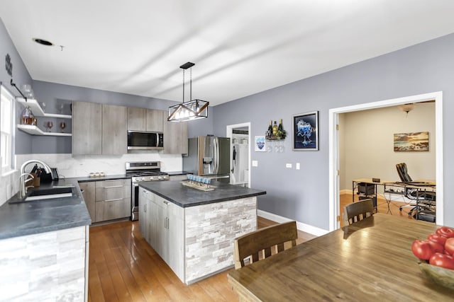 kitchen featuring a sink, appliances with stainless steel finishes, a center island, and dark countertops