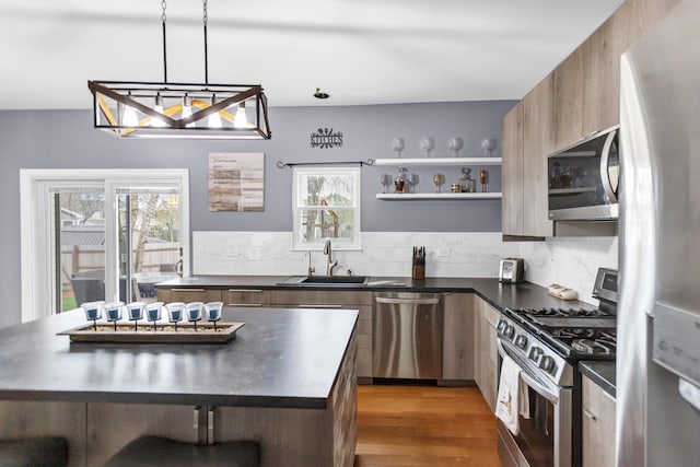 kitchen with dark countertops, appliances with stainless steel finishes, a sink, decorative backsplash, and modern cabinets