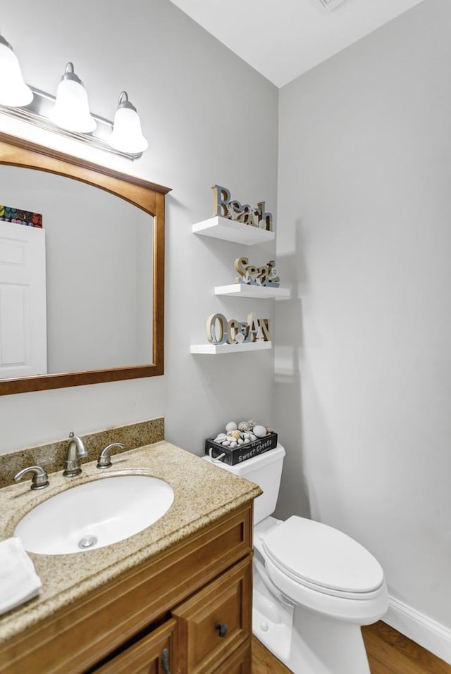bathroom with vanity, toilet, and wood finished floors
