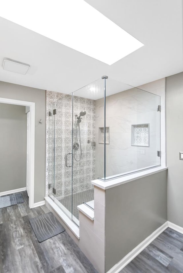 full bathroom with baseboards, a stall shower, and wood finished floors
