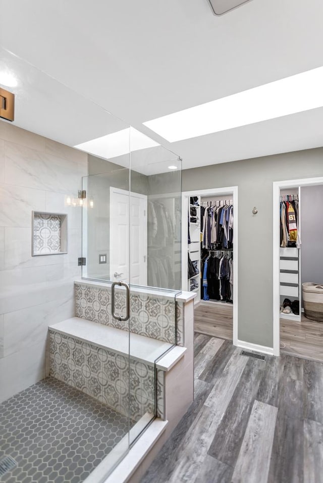 full bath with a shower stall, wood finished floors, and a spacious closet