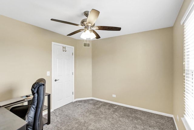 unfurnished office with carpet floors, ceiling fan, baseboards, and visible vents
