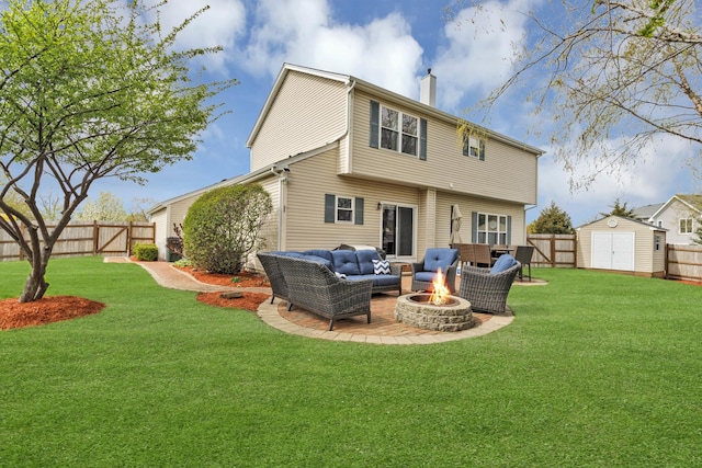 back of house with a chimney, a storage unit, a fenced backyard, and an outdoor living space with a fire pit