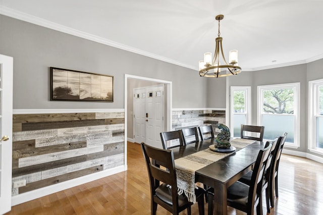 dining room with an inviting chandelier, baseboards, ornamental molding, and wood finished floors