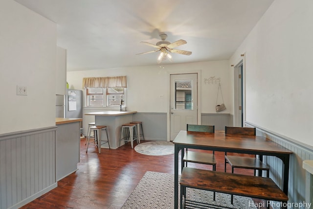dining room with a healthy amount of sunlight, a wainscoted wall, ceiling fan, and wood finished floors