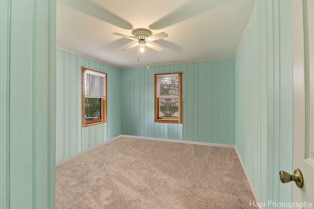 carpeted empty room with baseboards, ceiling fan, and ornamental molding