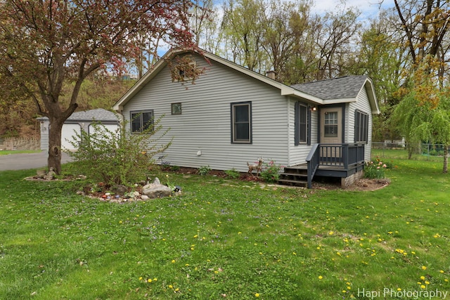 view of home's exterior with a shingled roof, fence, a yard, and a wooden deck