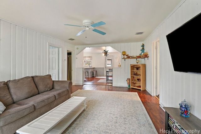 living room with arched walkways, a ceiling fan, dark wood finished floors, and visible vents