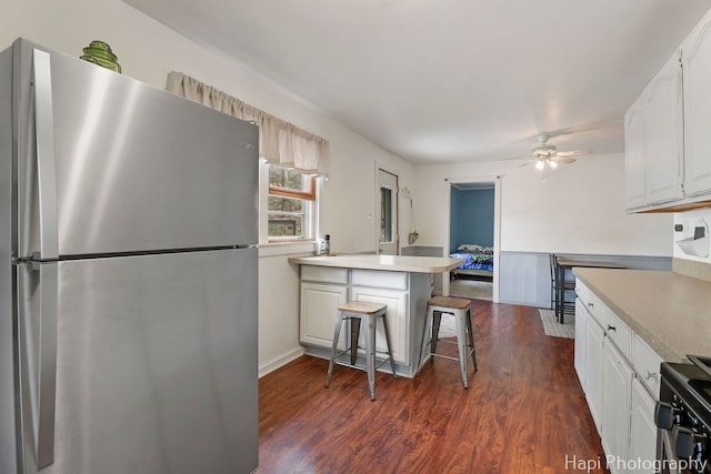 kitchen featuring ceiling fan, range with electric cooktop, freestanding refrigerator, a peninsula, and white cabinetry