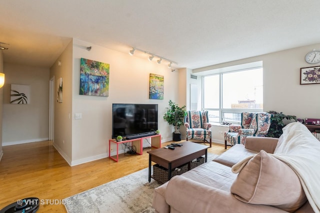 living room with rail lighting, baseboards, and light wood-type flooring
