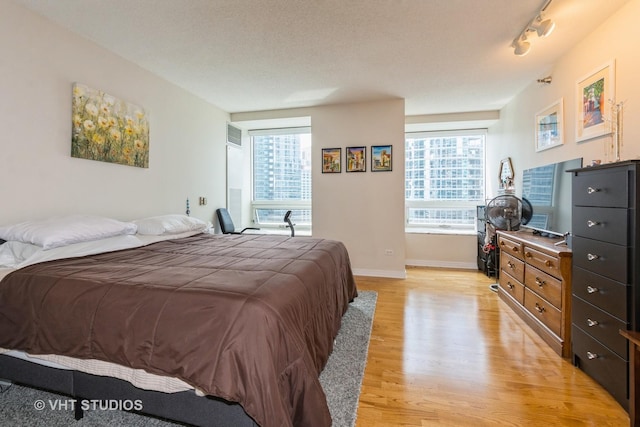 bedroom featuring baseboards, multiple windows, and light wood finished floors