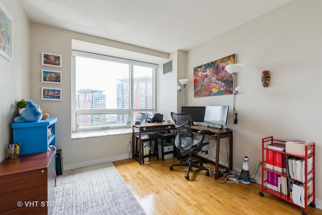office space featuring baseboards, wood finished floors, and visible vents