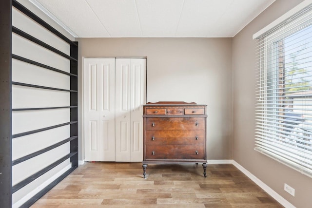 bedroom with baseboards, light wood finished floors, and a closet