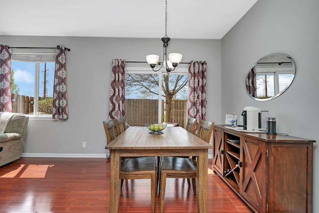 dining space featuring baseboards, dark wood-style flooring, and a notable chandelier