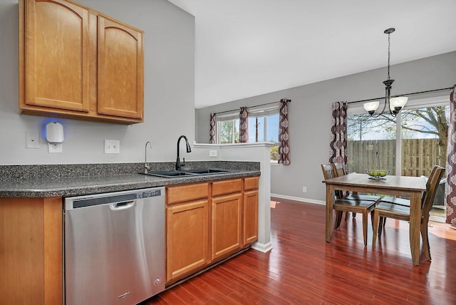 kitchen featuring dark countertops, a sink, dark wood finished floors, dishwasher, and a notable chandelier
