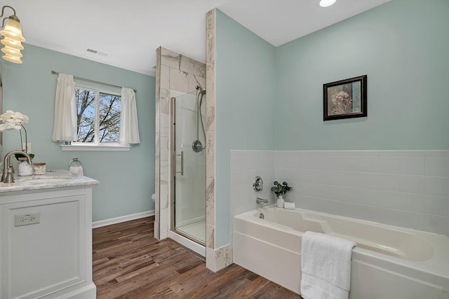 full bathroom featuring a bath, a shower stall, wood finished floors, and visible vents