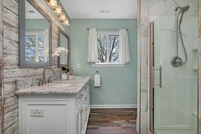bathroom featuring plenty of natural light, a shower stall, wood finished floors, and visible vents