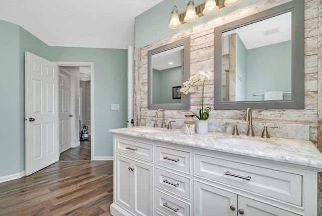 bathroom featuring double vanity, baseboards, a sink, and wood finished floors