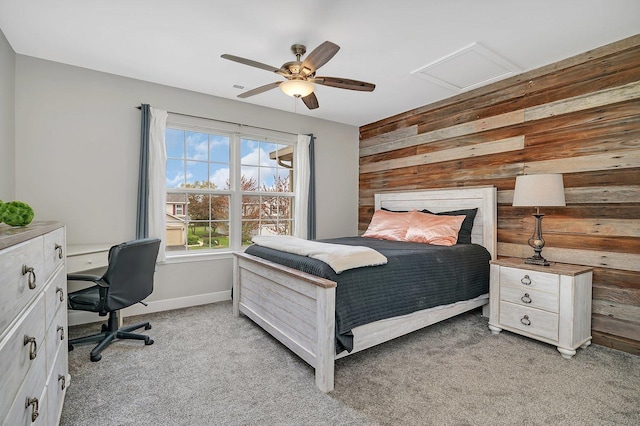 bedroom featuring baseboards, attic access, ceiling fan, wooden walls, and light colored carpet
