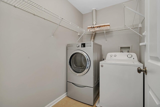 clothes washing area featuring laundry area, baseboards, and washing machine and dryer