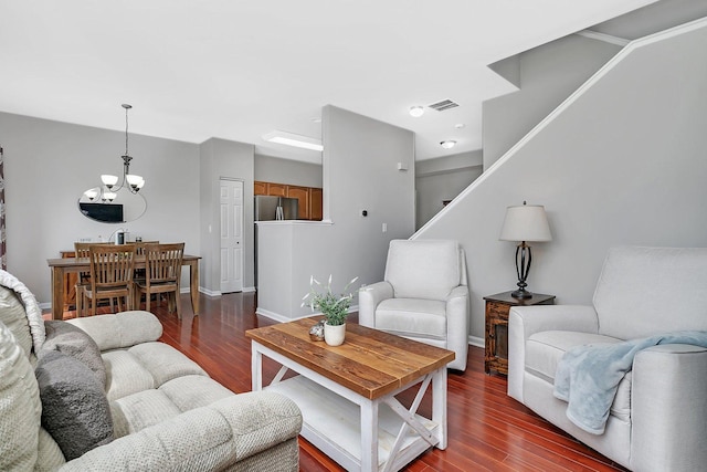 living room with visible vents, baseboards, dark wood-style floors, a chandelier, and stairs