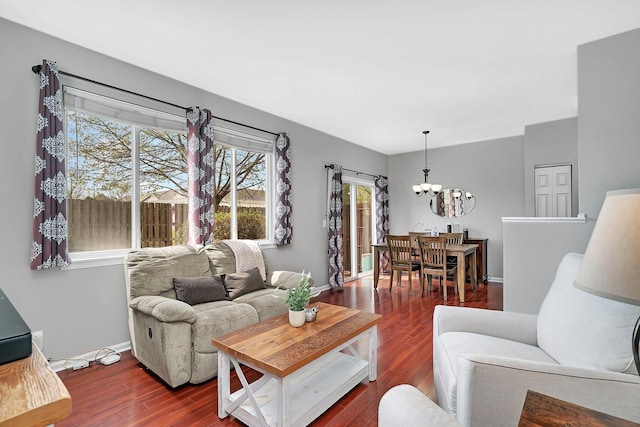 living room featuring an inviting chandelier, baseboards, and wood finished floors