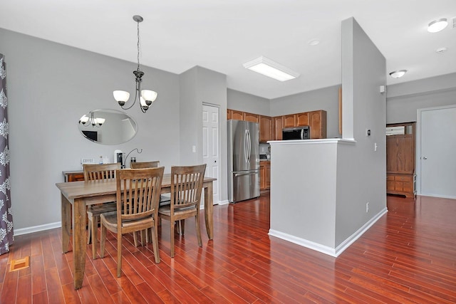 dining space featuring baseboards, dark wood finished floors, a chandelier, and visible vents