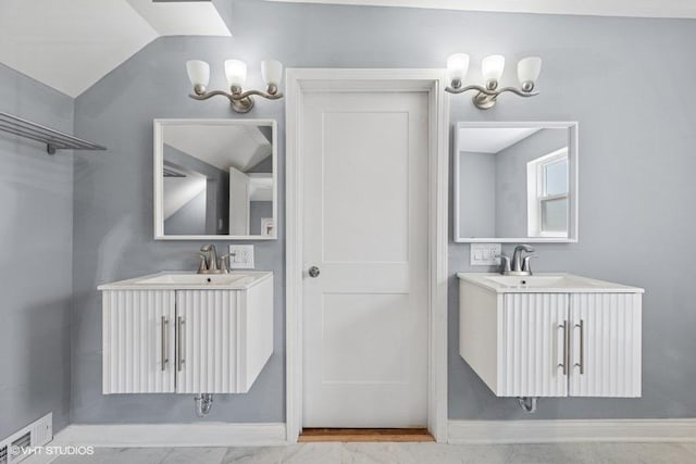 bathroom featuring baseboards, a sink, two vanities, and visible vents