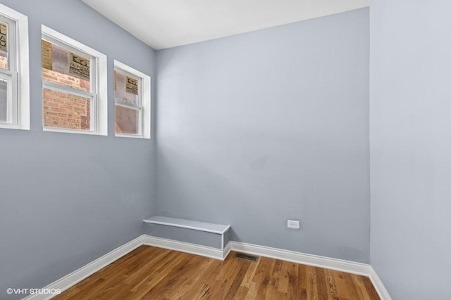 unfurnished room featuring baseboards, wood finished floors, and visible vents