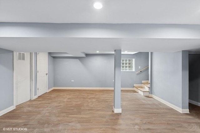below grade area with baseboards, stairs, wood finished floors, and visible vents