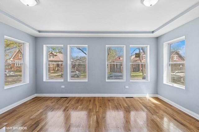 unfurnished room with baseboards, visible vents, and wood finished floors