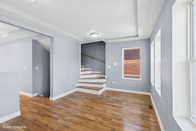 interior space featuring baseboards, stairs, wood finished floors, and visible vents