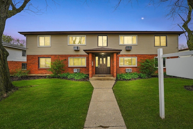 view of front of property featuring a lawn and brick siding