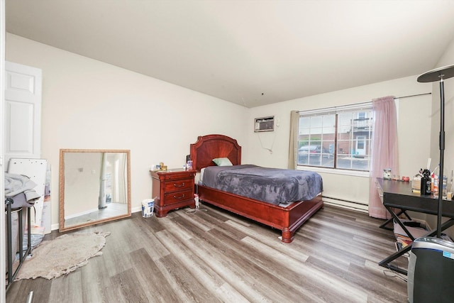 bedroom featuring a baseboard heating unit, light wood-style floors, baseboards, and an AC wall unit